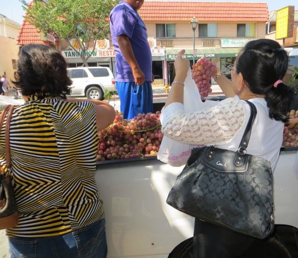 women buying grapes from steet vendor